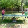 Persone giocano a ping pong all'aperto tra gli alberi.
