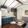 Piccola cucina con tavolo, sedie a righe, e armadietti blu.