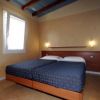 Camera con due letti singoli, pareti beige, luci soffuse e soffitto con travi in legno.