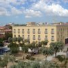Edificio beige a tre piani, circondato da alberi.