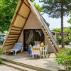 Bungalow a forma di A con terrazza tra alberi e cespugli.