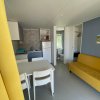 Cucina e soggiorno con divano giallo e sedie bianche.